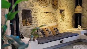 A modern living room with a stone wall, a sofa, and a fireplace. - NisUrla (Urla)