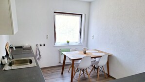 Une cuisine compacte comprenant un évier, une fenêtre avec vue et un coin repas avec une table et des chaises.