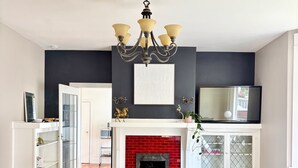 Un salon moderne avec un canapé bleu foncé, une cheminée blanche et un lustre.