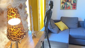 A living room with a sofa, a lamp, a sculpture, and a painting on the wall. - Old Antibes, 2 pcs sea view, air conditioning, beach 2min, restaurants, market (Antibes)