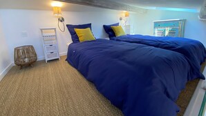 A bedroom with two beds, a small white nightstand, a wicker chair, and a window with shutters. - Old Antibes, 2 pcs sea view, air conditioning, beach 2min, restaurants, market (Antibes)