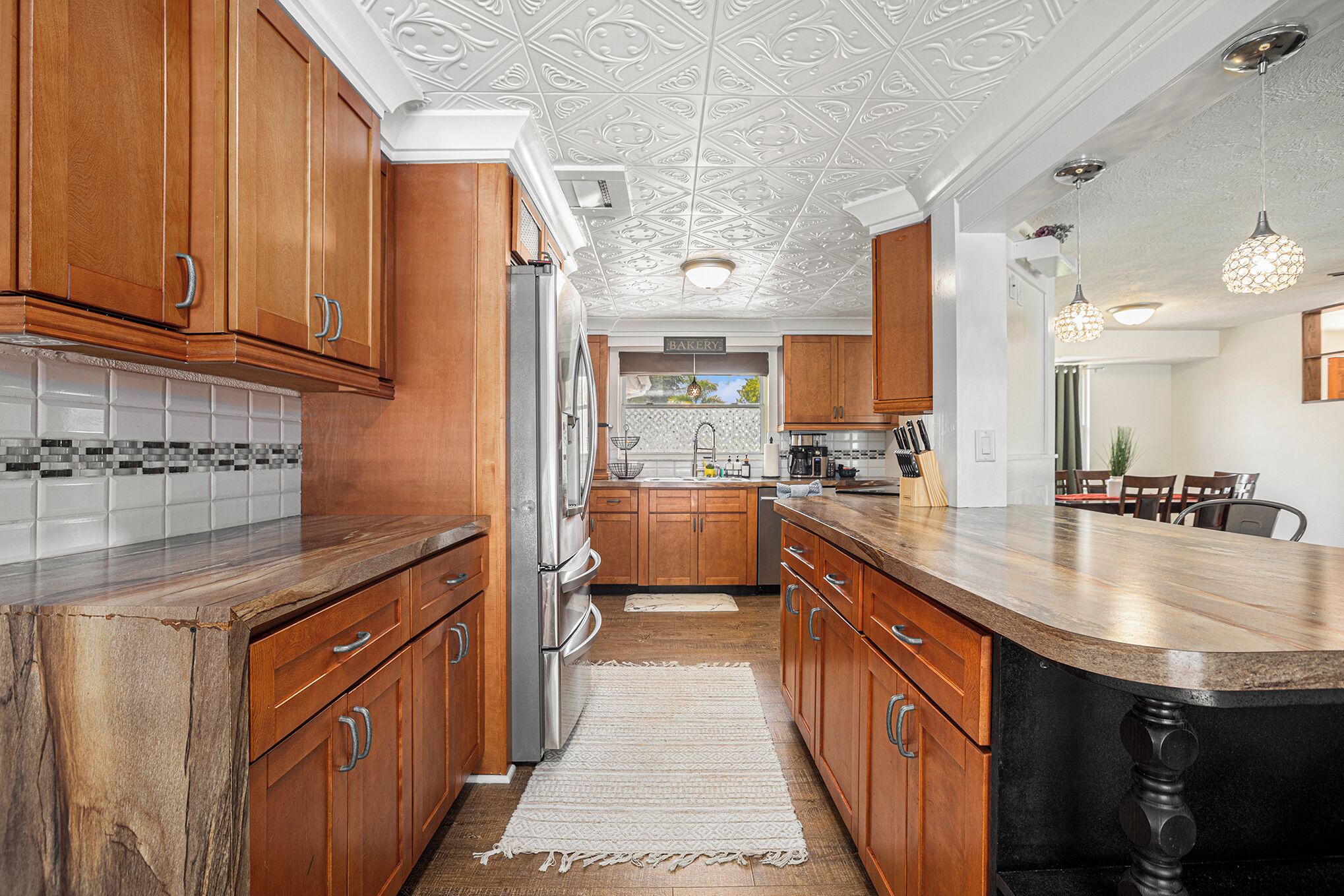 A kitchen with wooden cabinets, a stainless steel refrigerator, and a tiled backsplash.