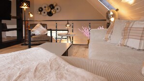 A cozy bedroom with a large bed, a smaller bed, a sofa, a table, and a chair. There are decorative items on the walls and a lamp on the table. - Lütt Heidjer Hus- Stylish oasis of peace. Guests with pets welcome (Buchholz in der Nordheide)