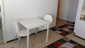 A small, white room with a white table and two white chairs. The floor has a patterned rug. - Flexible myllykallio (Jyväskylä)
