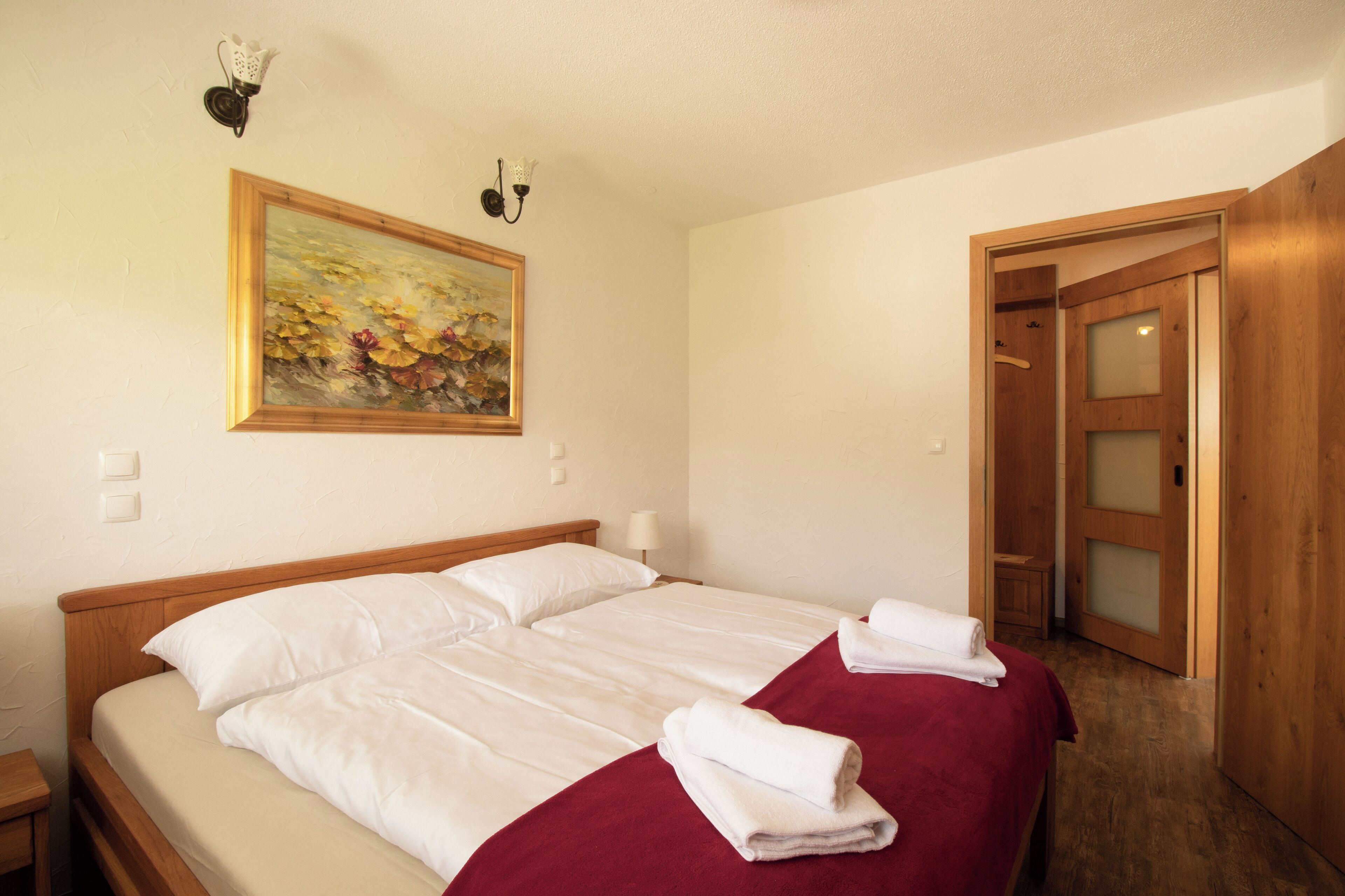 Ein Hotelzimmer mit einem großen Bett, einem Bild an der Wand, einem Holzschrank und einer Tür zu einem weiteren Raum.