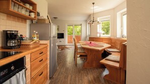 Eine Küche mit Holzausstattung, einem Kühlschrank, einer Kaffeemaschine und einem Essbereich mit Tisch und Stühlen.