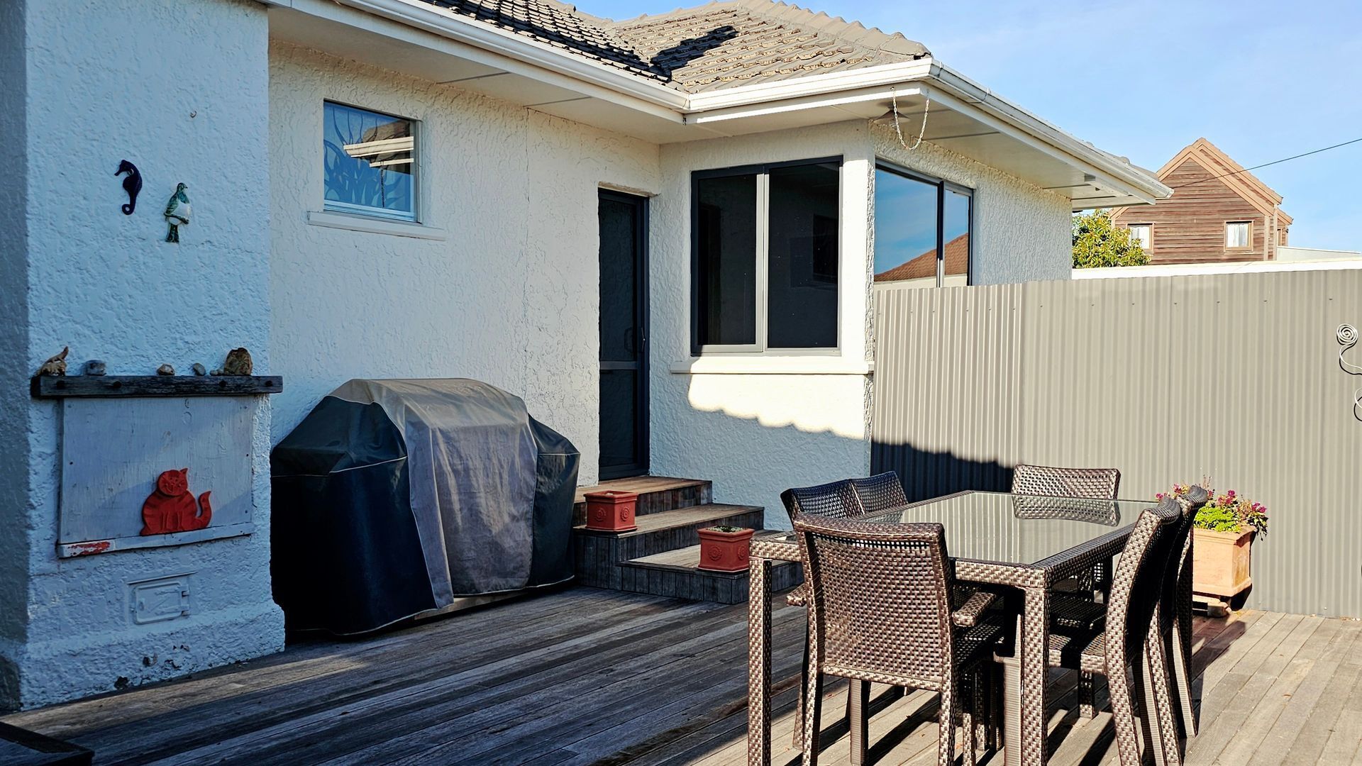 A patio with a table and chairs, a barbecue grill, and a covered deck area.