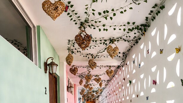 Ein Flur mit Holzboden, weißer Wand mit ausgestanzten Mustern und herzförmigen Anhängern.