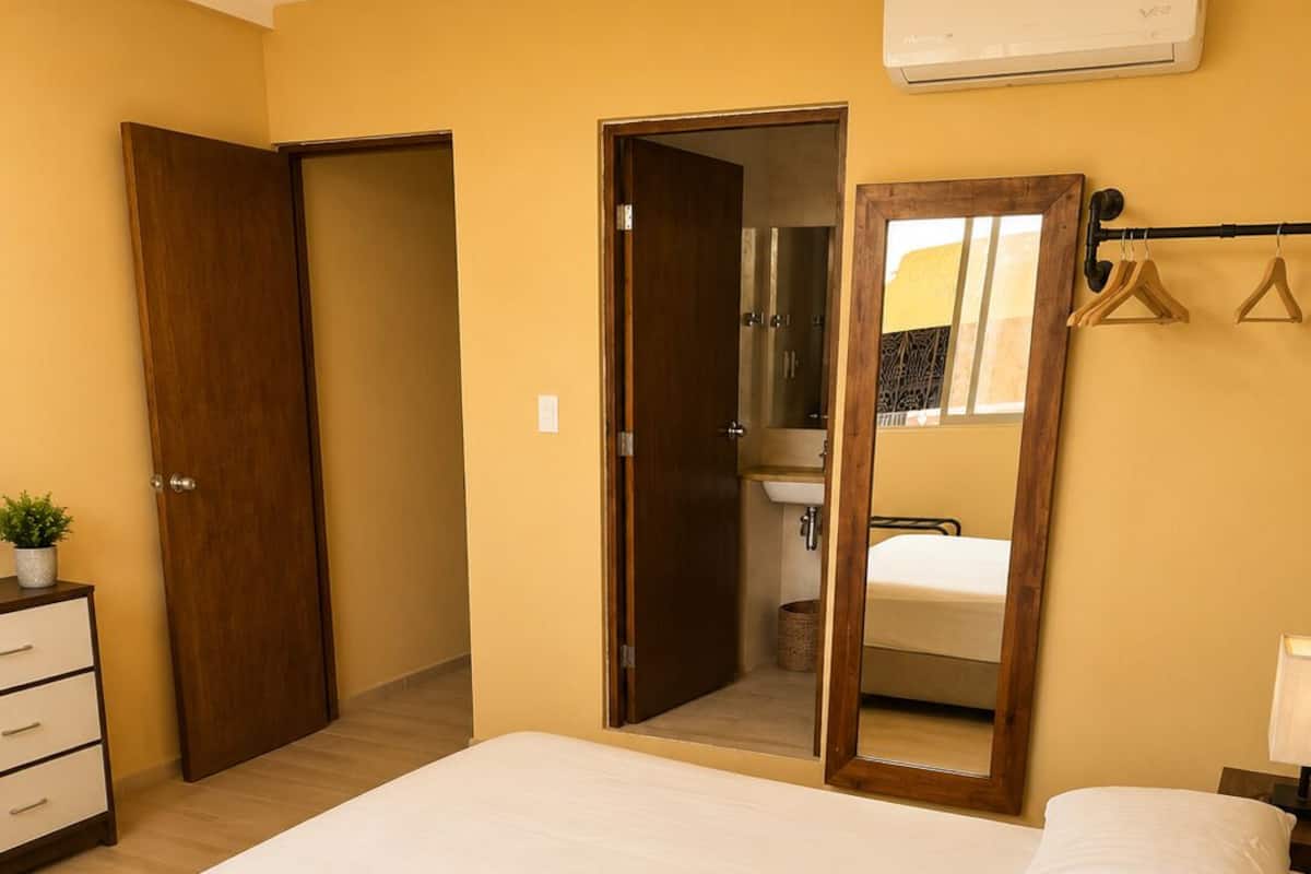 A bedroom with a bed, a dresser, a mirror, and a hanging rack.