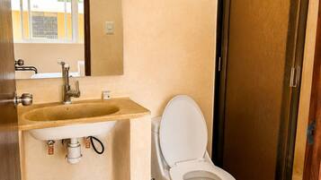 Une salle de bain avec des toilettes, un lavabo et un miroir.