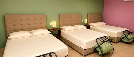 A hotel room with two beds, a green wall, a purple wall, and a wooden floor.