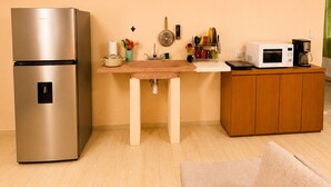Eine kleine Küche mit Kühlschrank, Mikrowelle, Kaffeemaschine und Spüle.