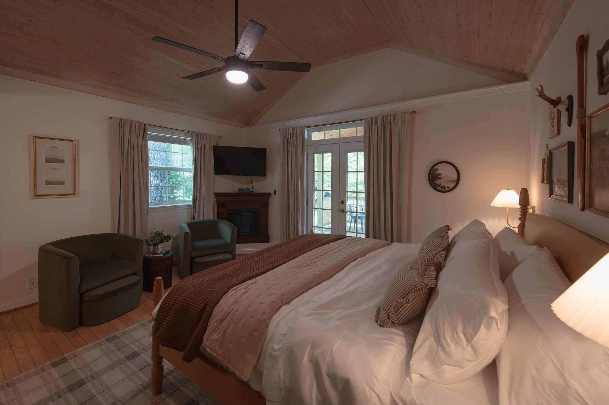 A bedroom with a bed, a chair, a television, and a fireplace.