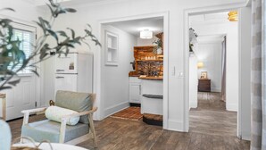 Un vaste espace de vie doté d’un plancher en bois, d’un coin salon avec un fauteuil confortable, d’une cuisine avec un plan de travail en bois et d’un coin repas avec une table et des chaises.