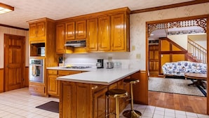 A kitchen with wooden cabinets, a central island, and bar stools.