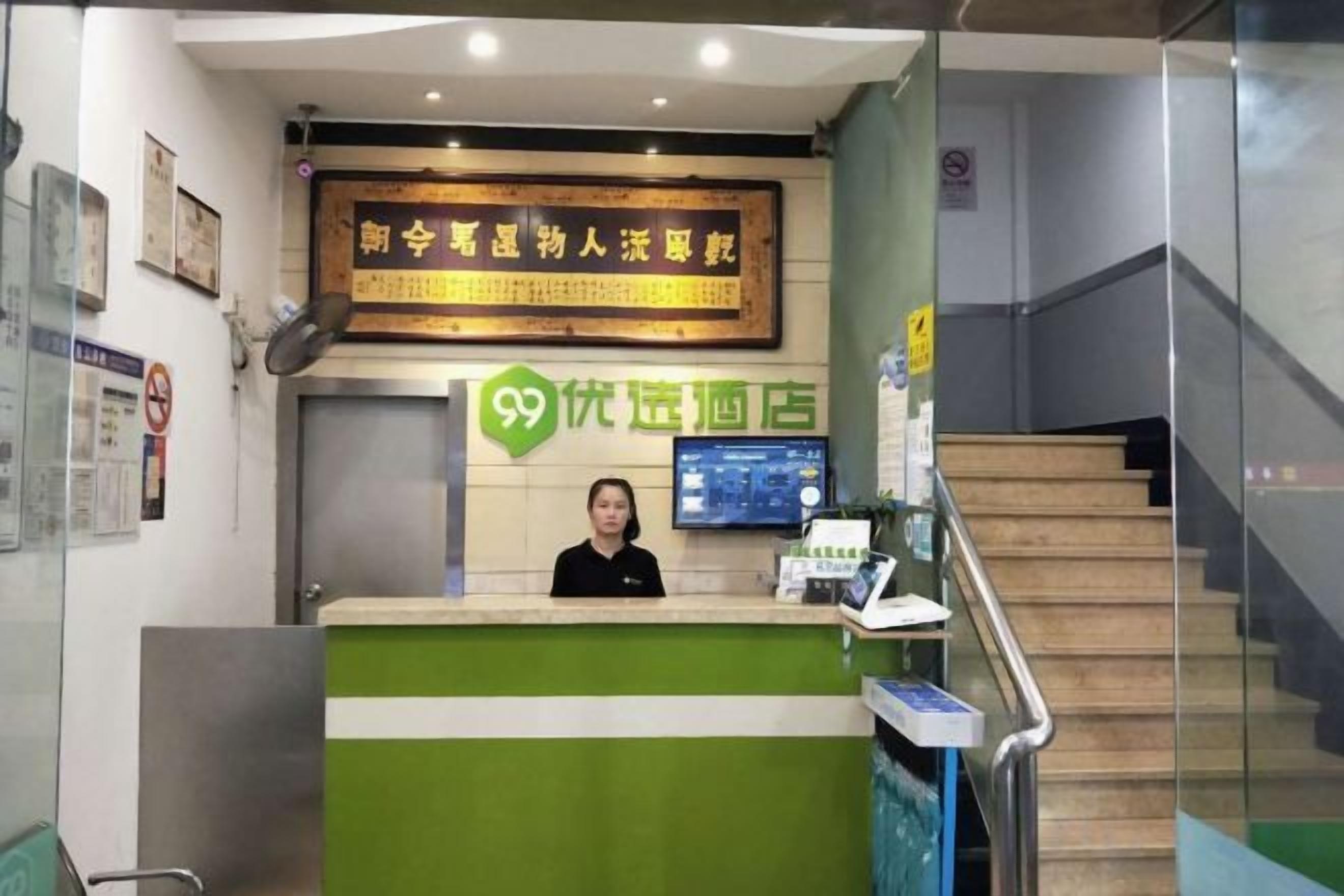 A reception area with a green counter, a digital screen, and a staircase.