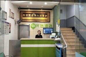 A reception desk with a digital screen, a sign with Chinese characters, and a staircase. - 99inn Selected (Shanghai South Station Metro Station) (Shanghai)