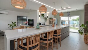Una cucina moderna con isola centrale, sedie in legno, luci a sospensione e vista sull'esterno.