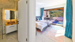 Un dormitori modern amb un llit gran, un bany amb un lavabo de marbre i un balcó amb piscina.