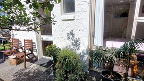 A courtyard with outdoor seating, potted plants, and a stone wall.