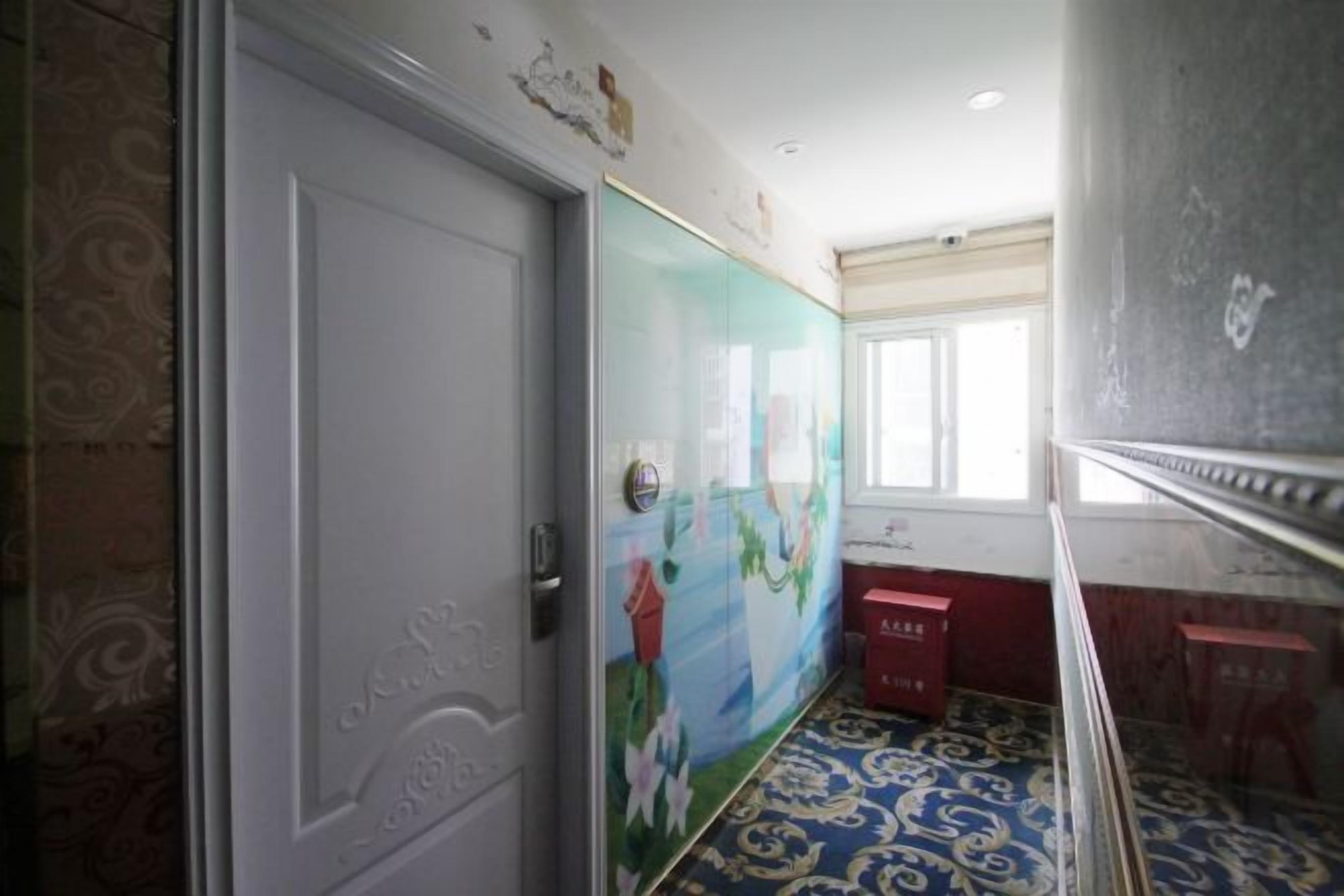 A hallway with patterned flooring, a door with intricate design, and a wall with a colorful mural.