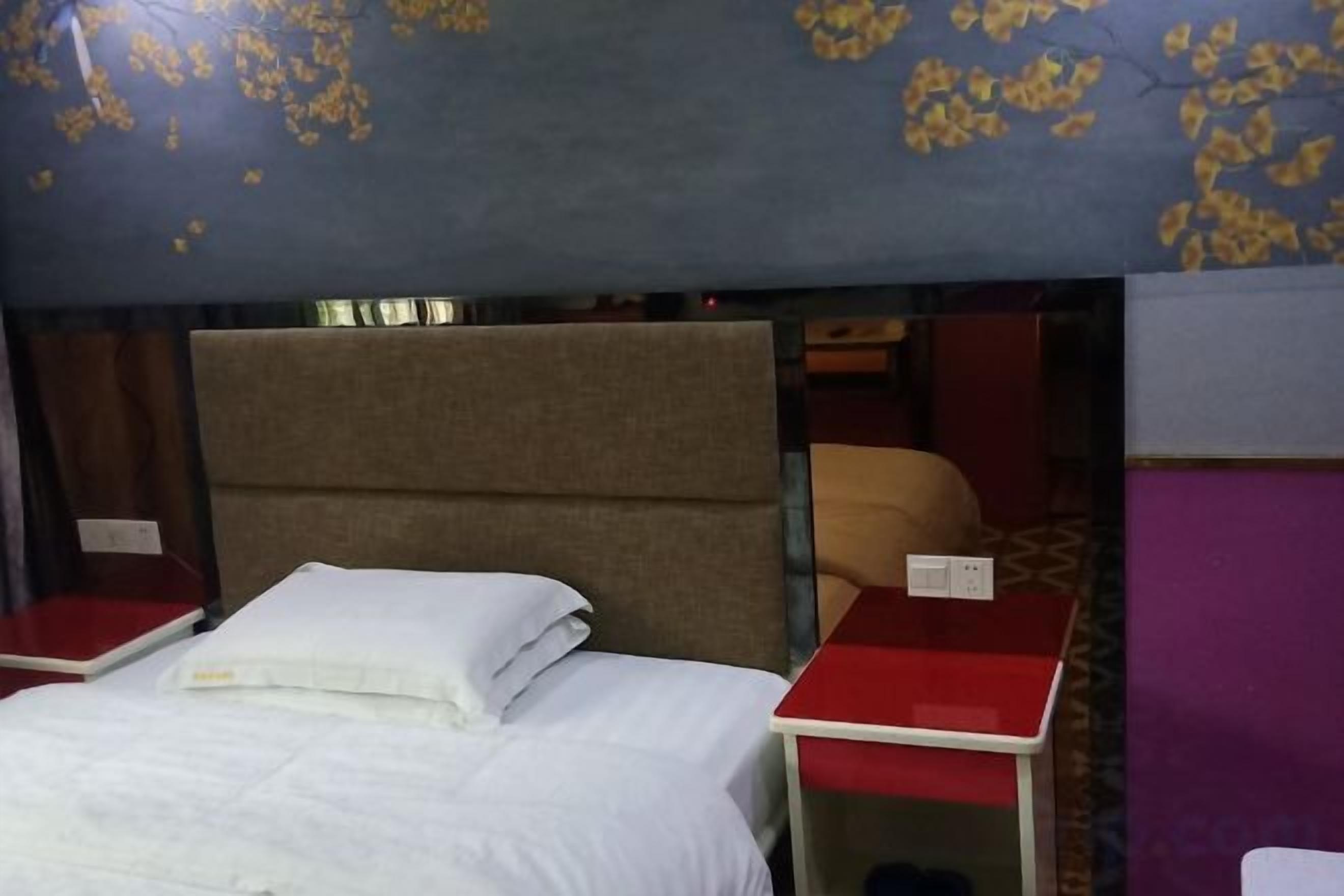 Ein Einzelbett mit Kopfteil, ein roter Nachttisch und ein kleiner Tisch.
