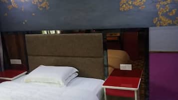 Ein Einzelbett mit Kopfteil, ein roter Nachttisch und ein kleiner Tisch.