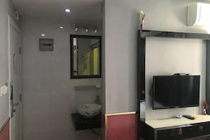 Une salle de bain équipée d’un lavabo, d’un miroir et d’un téléviseur fixé au mur.