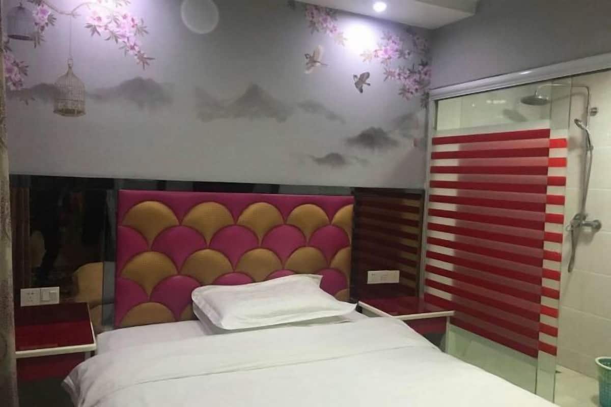 Une chambre d’hôtel avec un lit, une douche dotée d’une porte en verre à rayures et un mur orné d’une fresque représentant des fleurs et des oiseaux.