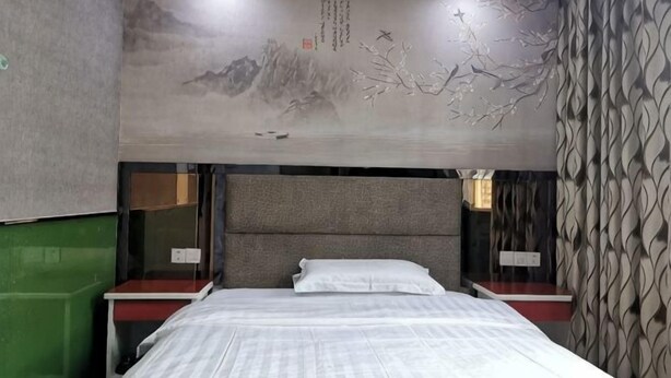 Ein Hotelzimmer mit Bett, Nachttischen, Wandgemälde und einer Wand mit Muster.