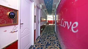 Ein Hotelkorridor mit Teppichmuster, einer digitalen Uhr und einer Wand mit dem Wort "Love".