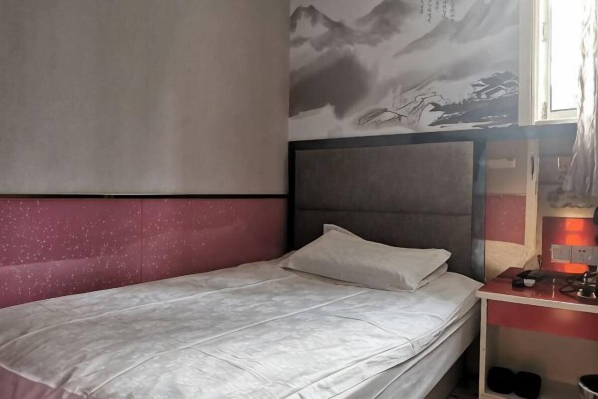 Une chambre à coucher comprenant un lit, une table de chevet, un miroir et une étagère fixée au mur.