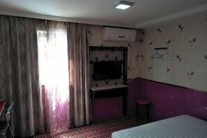 A hotel room with a bed, a desk, a chair, an air conditioning unit, and a television. - Xinhao Fashion Hotel (Shanghai)