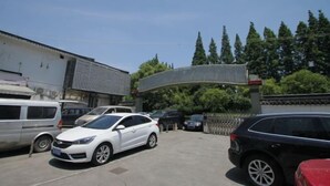Ein Parkplatz mit mehreren Autos, darunter eine weiße Limousine und ein schwarzer Geländewagen.