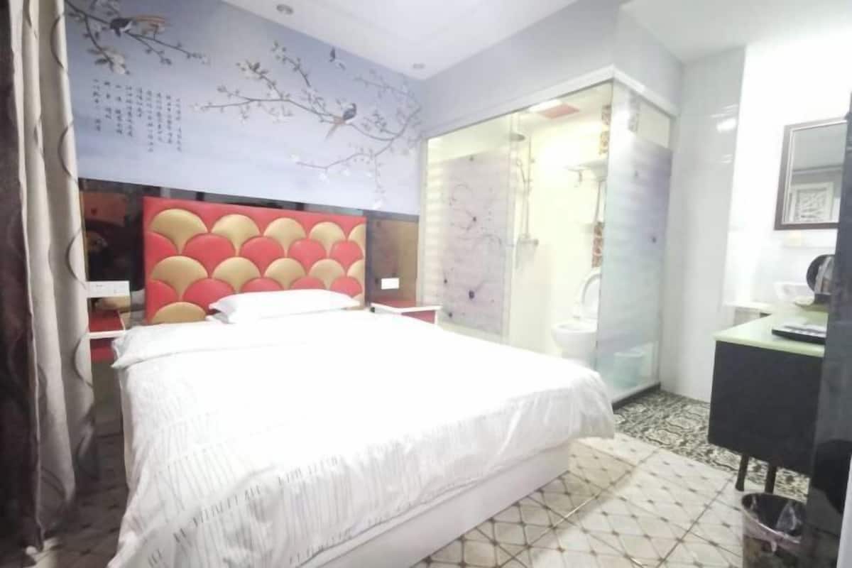Une chambre à coucher avec un lit, une armoire, un miroir et une petite table.