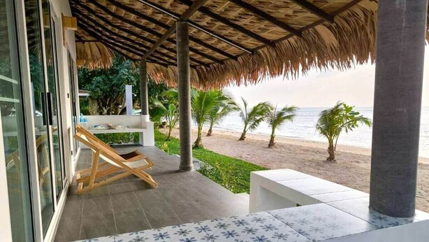 A beachside balcony with a thatched roof, a white outdoor seating area, and a view of the ocean. - Villa Sereno Beachfront Koh Samui (Koh Samui)