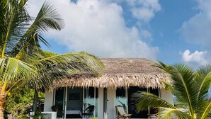 A beachfront property with a thatched roof, a covered outdoor seating area, and a view of the ocean. - Villa Sereno Beachfront Koh Samui (Koh Samui)