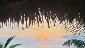 A beach scene with a sunset, palm trees, and calm water. - Villa Sereno Beachfront Koh Samui (Koh Samui)