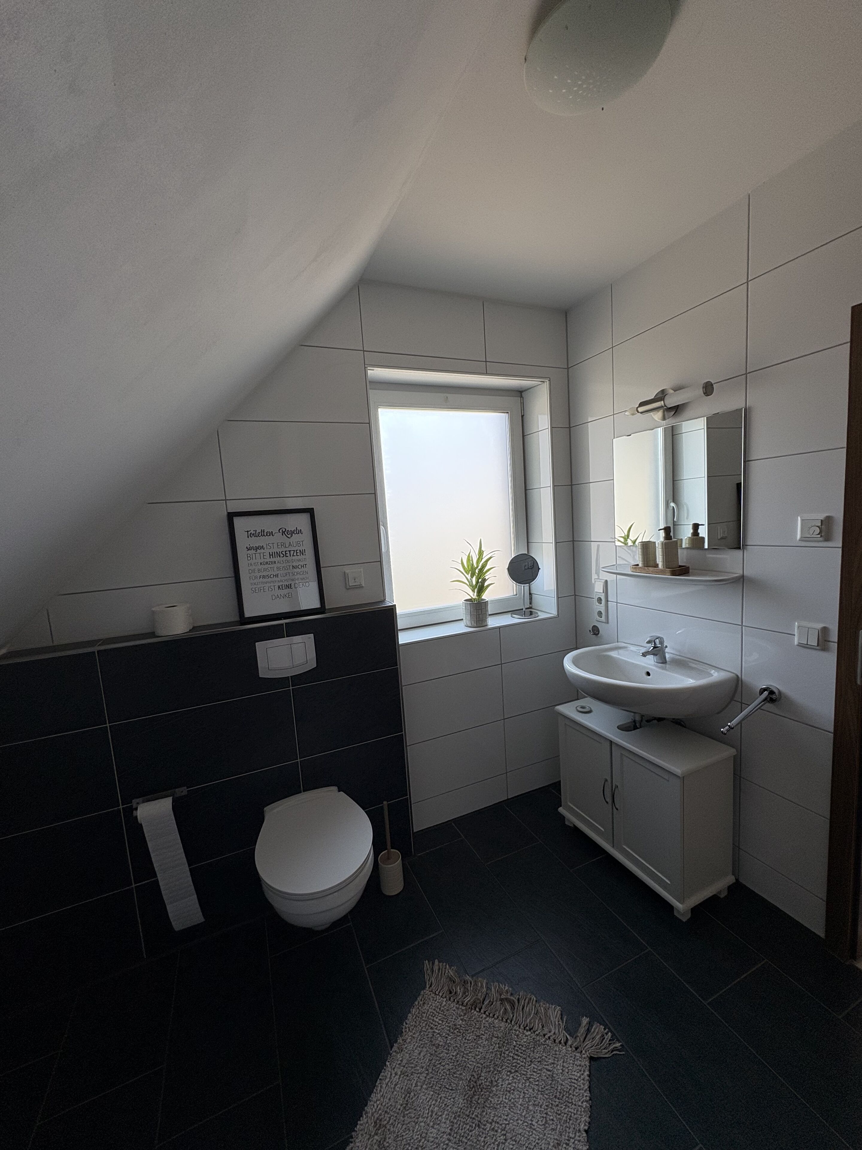 Une salle de bain moderne avec des toilettes, un lavabo et une fenêtre.
