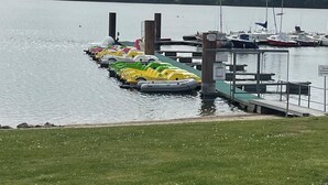 A marina with boats docked, a grassy area in the foreground, and a cloudy sky. - Vacation apartment directly on the lake (Kalkar)