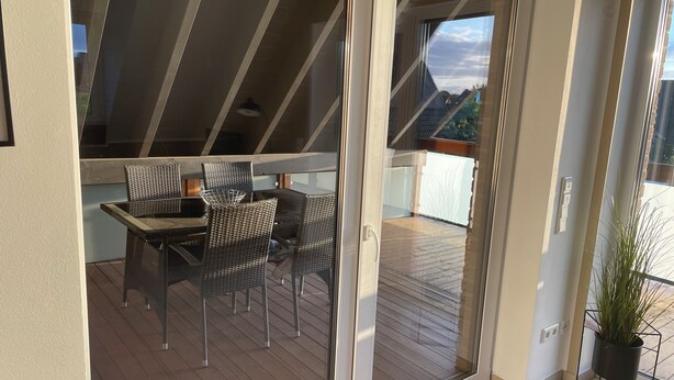 A modern outdoor patio with a glass door leading to a wooden deck. - Vacation apartment directly on the lake (Kalkar)