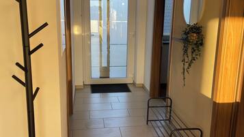 A hallway with a coat rack, a small bench, a door leading outside, and a wall-mounted mirror.