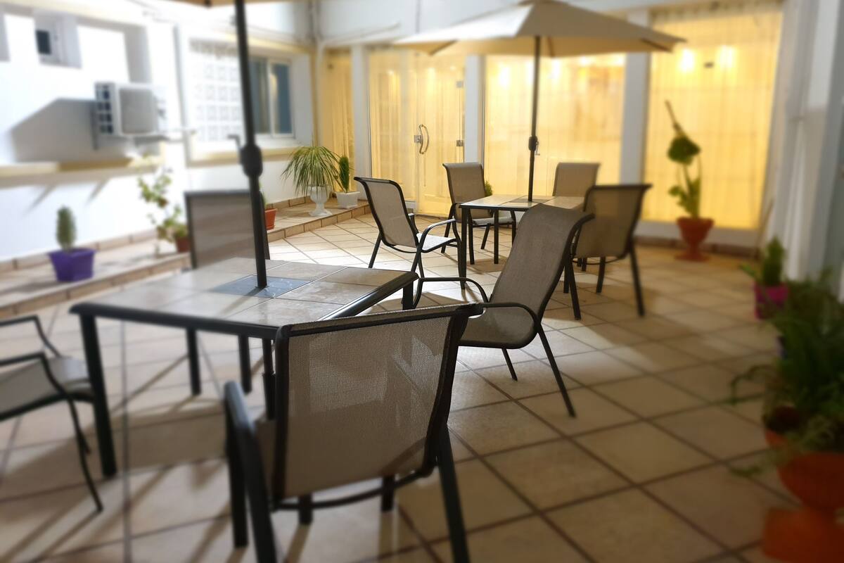A patio area with outdoor seating, including tables and chairs, and potted plants.