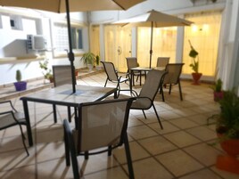 A patio area with outdoor seating, including tables and chairs, and potted plants.