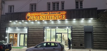 A hostel restaurant named 'Aresidence' with a modern facade, large glass doors, and a car parked in front.