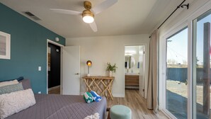 A bedroom with a bed, bedside table, and a view through a large window. - Pool, Hot Tub Heating, BBQ, AC & Private Yard, Pet Friendly, 10mins to JTNP! (Joshua Tree)