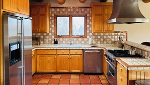 Une cuisine dotée de meubles en bois, d’un réfrigérateur en acier inoxydable, d’un lave-vaisselle, d’une cuisinière et d’une fenêtre offrant une vue agréable.