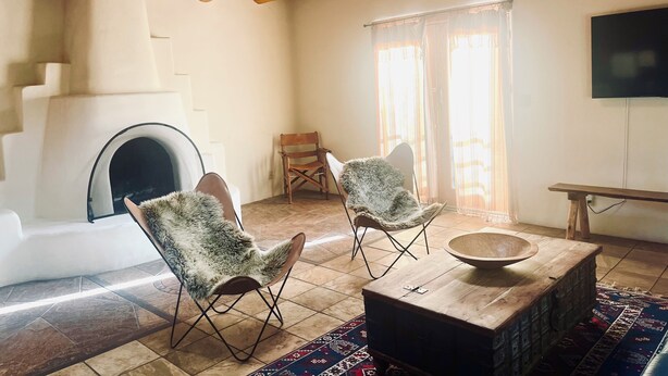 Un salon chaleureux avec une cheminée, deux fauteuils, une table basse en bois et un téléviseur.