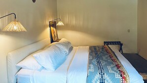 Une chambre à coucher comprenant un lit, une table de chevet, une lampe et une œuvre d’art accrochée au mur.