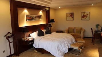 Une chambre d’hôtel avec un grand lit, une table de chevet, une chaise et des œuvres d’art accrochées aux murs.
